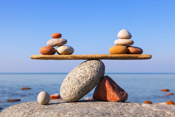 échelles symboliques des pierres contre la mer. concept de avantages et de inconvénients - équilibre photos et images de collection