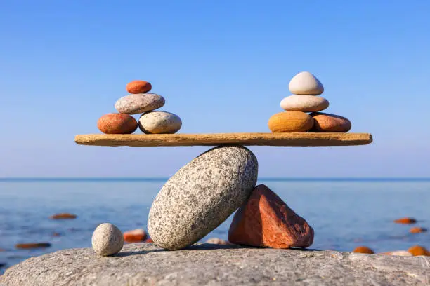 Photo of Symbolic scales of the stones against the sea. Pros and cons concept