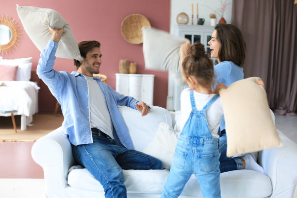 istock Happy young family having fun with pillows on sofa. 1254419456