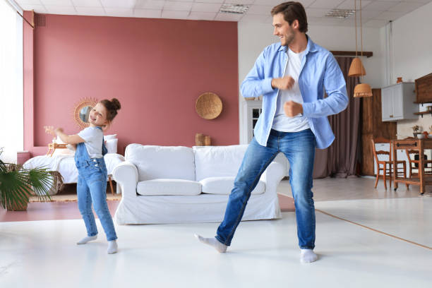 istock Handsome young man dancing at home with his little cute daugther. 1254419557