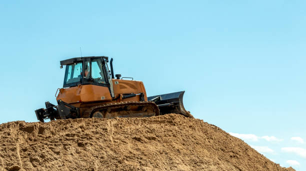 uma escavadeira em uma grande pilha de areia contra um céu azul - caterpillar truck - fotografias e filmes do acervo