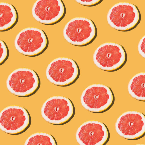 istock Pink ripe grapefruit slices on the orange background pattern. 1254420772