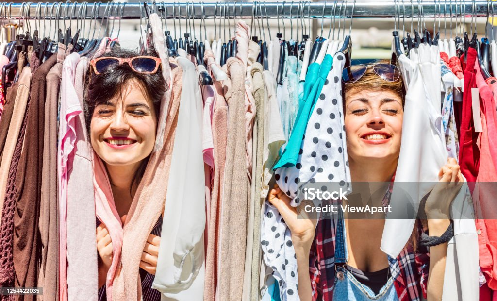 Happy women at weekly flea market - Female friends having fun together shopping cloth on sunny day - Millenial lifestyle concept with girlfriends enjoying everyday life moments - Bright vivid filter Shopping Stock Photo