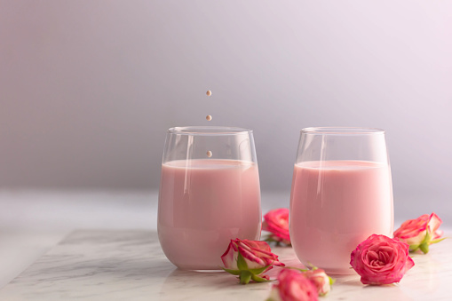 Rose moon milk for a better sleep with little splash in a glass. Ayurveda warm drink consumed before bed. Nice in case of sleeplessness, anxiety and insomnia