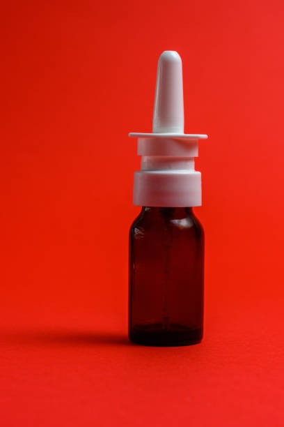 vaporisateur nasal dans la bouteille foncée avec la buse sur le fond rouge. - medicine cabinet medicine nasal spray human nose photos et images de collection