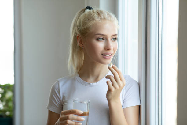 mujer tomando píldora con aceite de hígado de bacalao omega-3 - cod liver oil capsule vitamin pill vitamin e fotografías e imágenes de stock