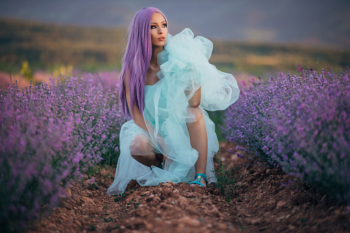 One woman, beautiful woman with purple hair in white dress on lavender field outdoors.