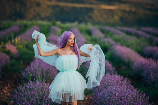 One woman, beautiful woman with purple hair in white dress on lavender field outdoors.