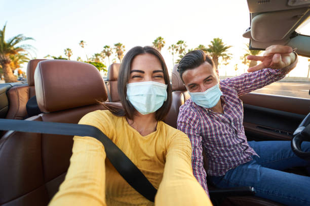 Young couple wearing masks taking selfie in a car stock photo