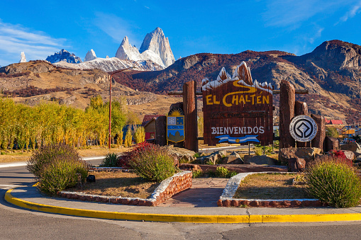 Road sign at the entrance of El Chalten village and Fitz Roy mountain on background. El Chalten located in Patagonia in Argentina.