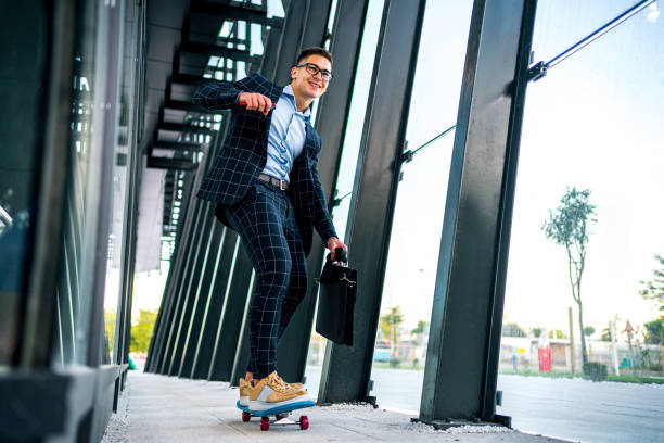 junger geschäftsmann auf skateboard - worklife balance stock-fotos und bilder