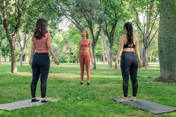 Three women doing yoga in the park. Tadasana pose