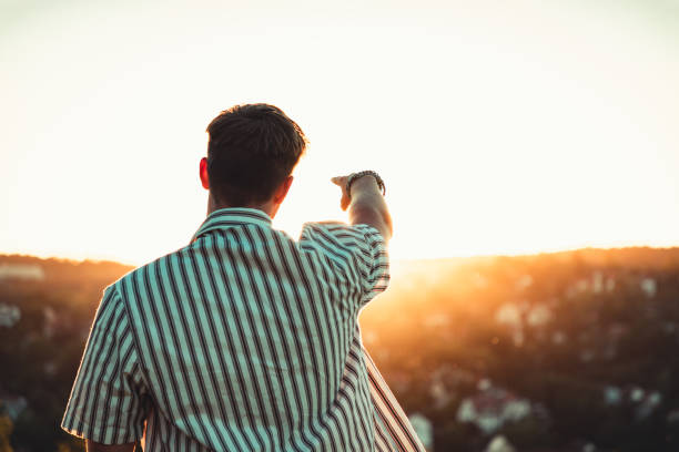istock Pointing to the Sunset Sun Young Man Outdoors 1254436791