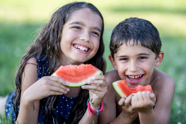 istock Hispanic siblings enjoying watermelon on a sunny afternoon 1254439101
