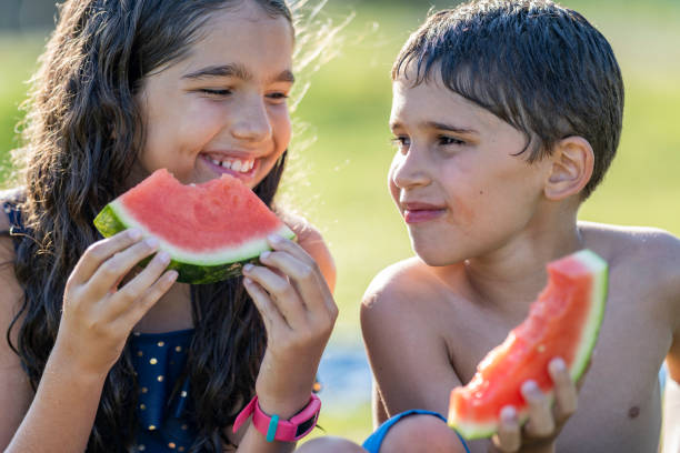 istock Hispanic siblings enjoying watermelon on a sunny afternoon 1254439405