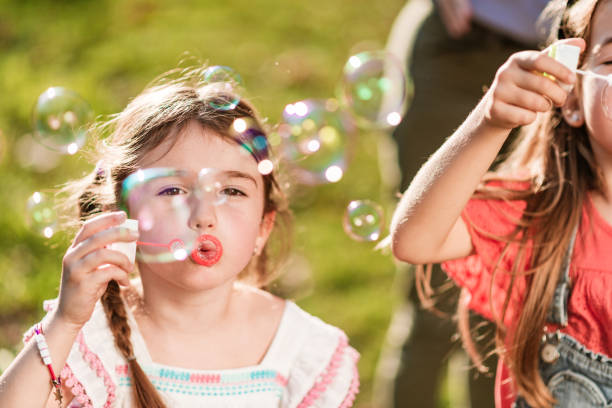 istock Happy kids blowing bubbles at public park 1254440939