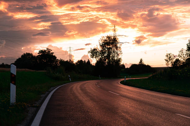 istock Empty Winding Country Road Roadside under dramatic Sunset Sky 1254442060