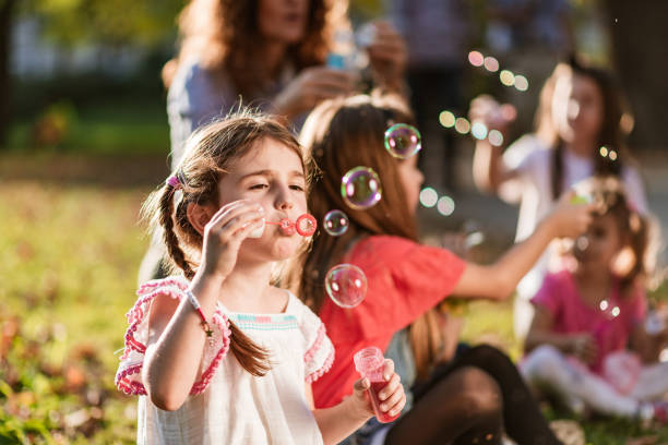 istock Happy kids blowing bubbles at public park 1254442750