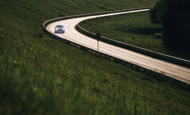 istock Fast modern car moving by the highway illuminated with back evening sun light. Safety auto traveling concept image. 1254446967