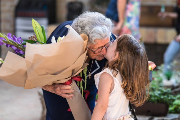 dziecko dające babci bukiet kwiatów i całujące ją - grandmother giving gift child zdjęcia i obrazy z banku zdjęć