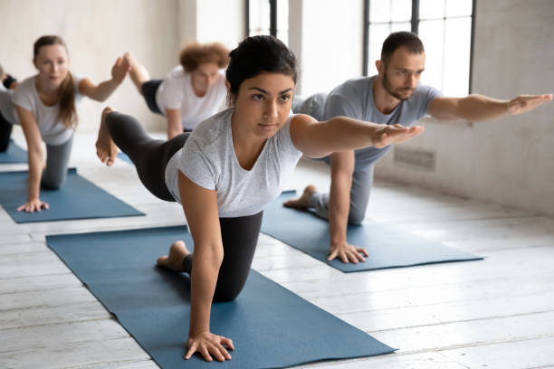 istock Young indian trainer showing bird dog pose at yoga class. 1254455291