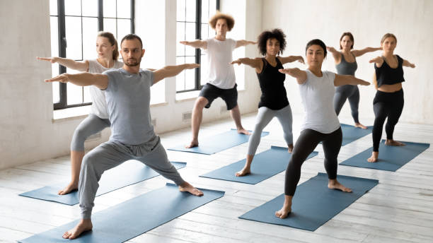 istock Young male trainer leading yoga class for concentrated multiracial students. 1254455320