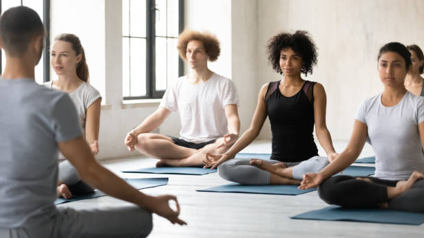 istock Focused peaceful young mixed race people learning meditating indoors. 1254455328
