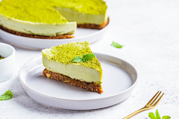 Piece of raw vegan matcha cake on a gray plate. Raw vegan matcha cheesecake on a gray plate. low carb diet photos stock pictures, royalty-free photos & images