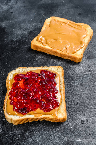 istock Peanut butter sandwich  toast with berry jam.  Black background. Top view 1254456644