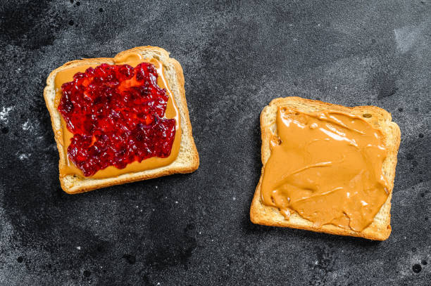 istock Peanut butter sandwich  toast with berry jam.  Black background. Top view 1254457535