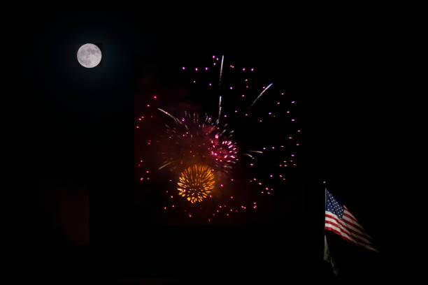 This photo was taken during a full moon and shows a firework display along with an American flag flying on a pole.  The shot was taken from a distance so that the moon, fireworks, and flag are all in focus and in frame.  Illumination levels of the moon and fireworks were seperately adjusted so that details of both are clear.