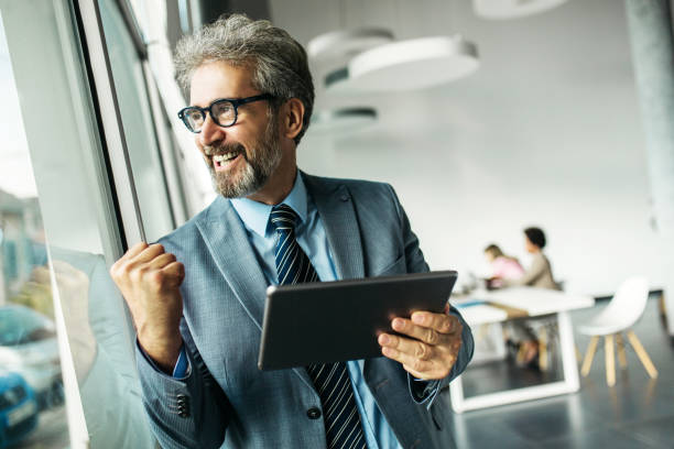 istock Happy senior businessman standing next to window 1254460537