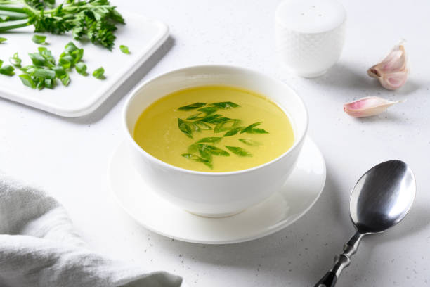 istock Chicken broth with green onion in white bowl on white table. Copy space. 1254465851