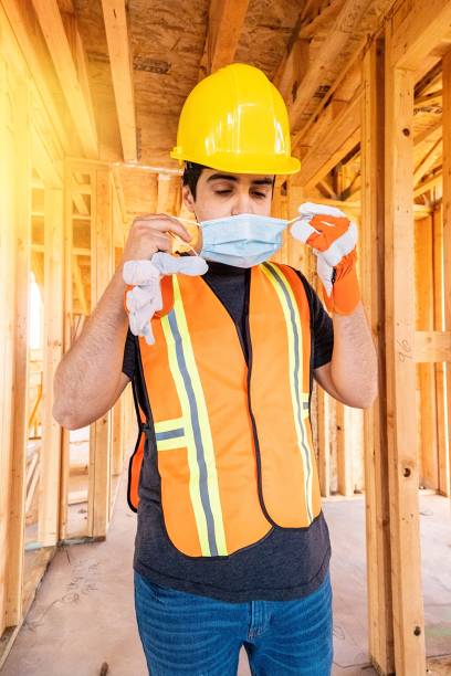 istock Young male construction worker putting on a protective face mask 1254466517