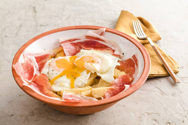 broken fried eggs with potatoes and iberian cured ham at spanish restaurant - smashed potatoes imagens e fotografias de stock