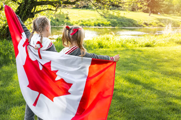 conceito de celebrtação do dia da canda feliz. duas crianças bonitas com bandeira canadense. visão traseira - canada day fotos - fotografias e filmes do acervo