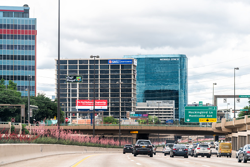 Dallas, USA - June 7, 2019: Highway 75 in modern city in summer with cars in traffic with signs for SMU and Merrill Lynch and exit for downtown