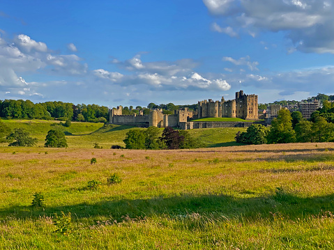 Alnwick, England, United Kingdom – June 20, 2020: Alnwick Castle is a medieval castle along the River Aln and private home to the 12th Duke of Northumberland. It is also a very popular filming location (Harry Potter, Downton Abbey, etc.). This view point overlooks both the castle as well as a country park.