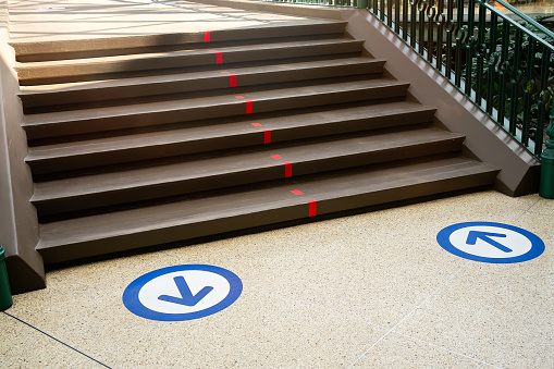 Epidemic protection measures in shops, shopping malls or centres floor blue circle stickers with arrow . Social Distance Shopping. Life after virus. Secure marking of lines on floor for directions,