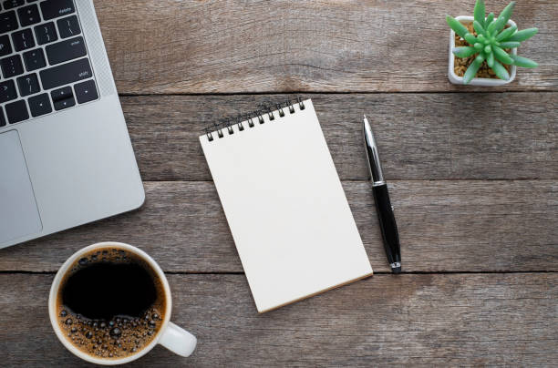 istock Top view from above of Blank open notebook, keyboard with coffee cup on wood table background. Workplace creative at home. Flat lay, Business-finance or education concept with copy space. 1254481155