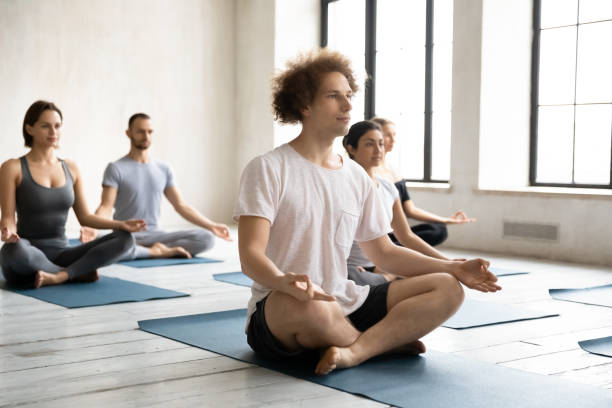 istock Focused young man sitting on yoga mat in lotus pose. 1254486383