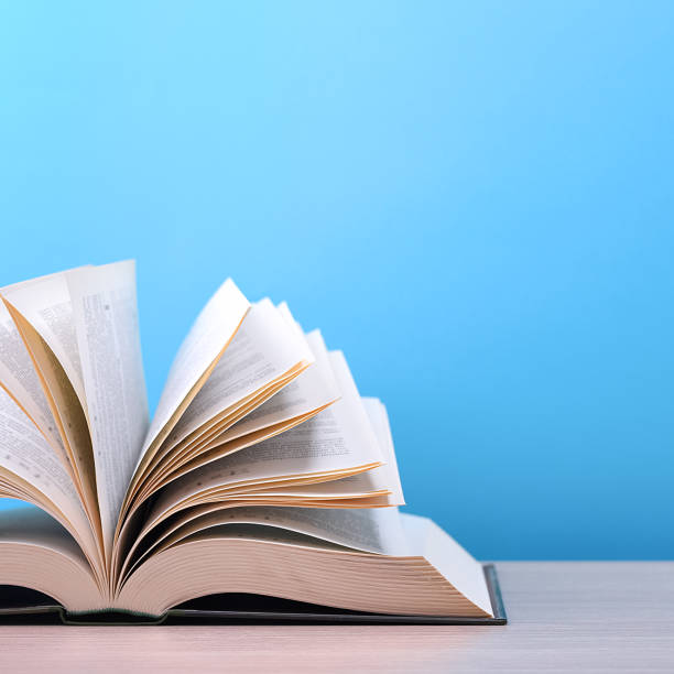 istock The book is open, lying on the table, sheets fanned out on a blue background. 1254489130