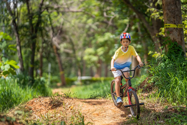o garoto asiático está treinando para um feliz mountain bike. - pedal bicycle sports training cycling - fotografias e filmes do acervo