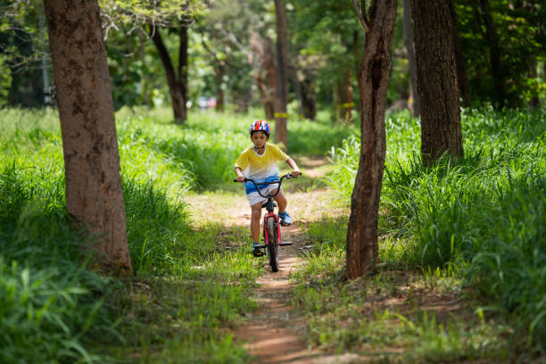 o garoto asiático está treinando para um feliz mountain bike. - pedal bicycle sports training cycling - fotografias e filmes do acervo