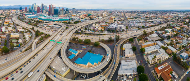 The remote scenic aerial view of Downtown Los Angeles from West Washington Boulevard, over the huge overpass crossing between Santa Monica Freeway and Harbor Freeway and Transit Way. High resolution stitched panorama. The remote scenic aerial view of Downtown Los Angeles from West Washington Boulevard, over the huge overpass crossing between Santa Monica Freeway and Harbor Freeway and Transit Way. California, USA. The cloudy afternoon of the autumn day. 4K UHD drone video footage with the backward camera motion. los angeles traffic jam stock pictures, royalty-free photos & images