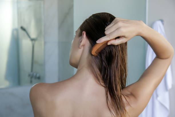 cuidado del cabello. mujer morena peinando el cabello húmedo con peine de madera. - peine fotografías e imágenes de stock