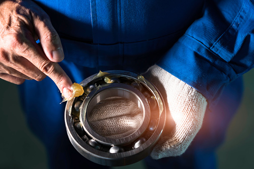 Mechanic is putting yellow grease in the into bearing, engineering and industrial concept