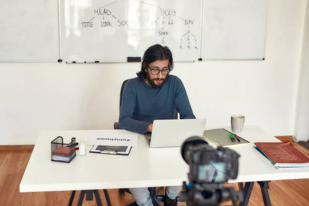 istock Working from home. Focused male teacher working on laptop while sitting at his workplace and teaching computer science online 1254496272