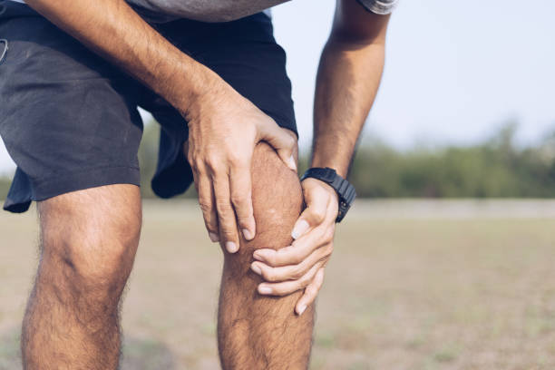 istock Close up young man hands  knee injury while exercise or running, 1254497120