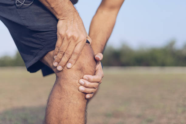 istock Close up young man hands  knee injury while exercise or running, 1254497190